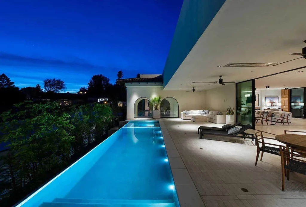 Rehab centre with an infinity pool and luxurious outdoor relaxation zone including a corner sofa, sun-loungers, and dining area